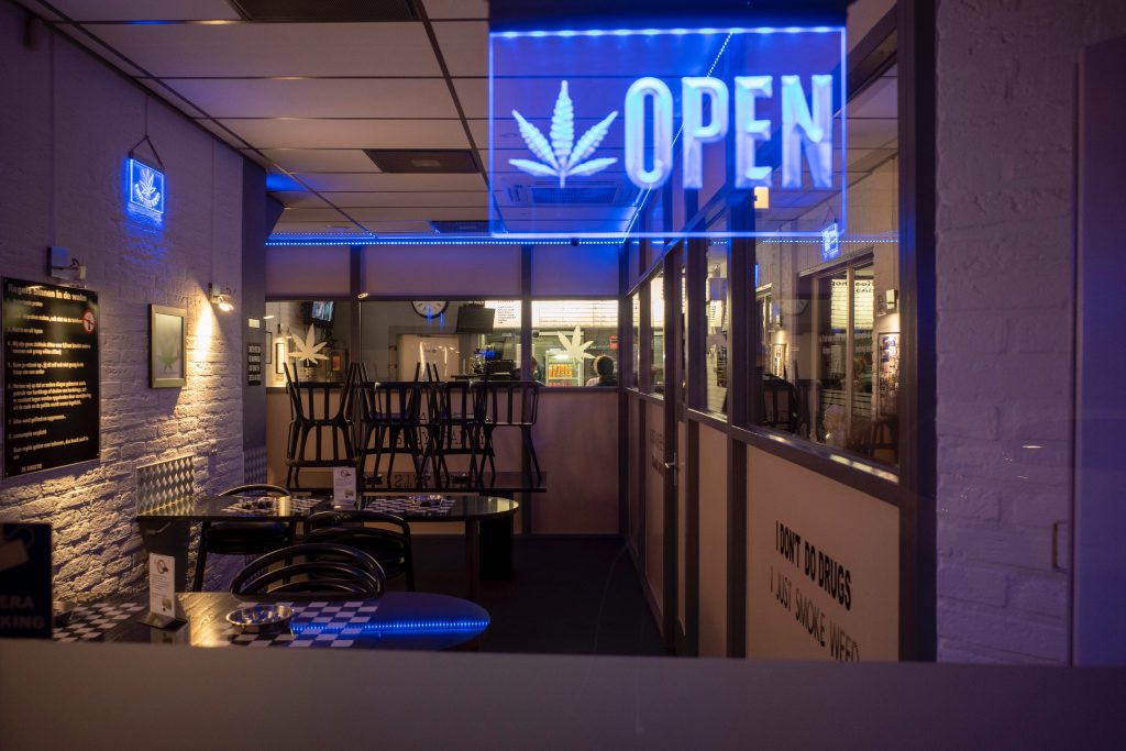 A lit sign with a picture of a marijuana leaf and the word