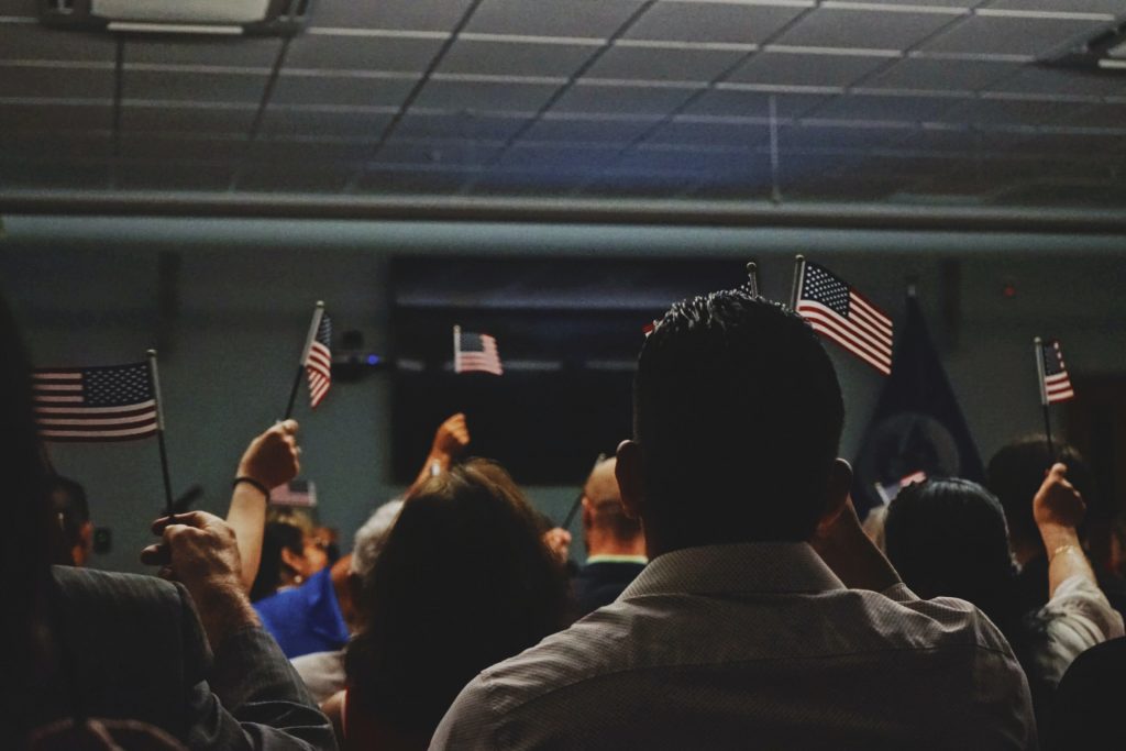 A group of people holding small American flags shown from behind.